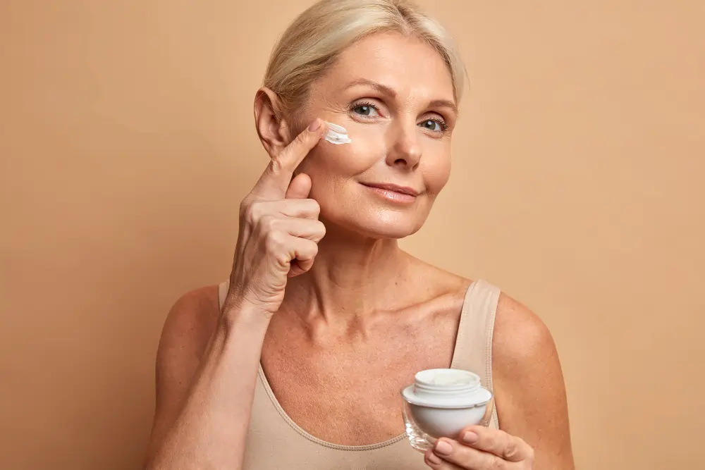 Woman applying anti-ageing skincare cream to reduce fine lines as part of an effective daily anti-ageing skincare routine.